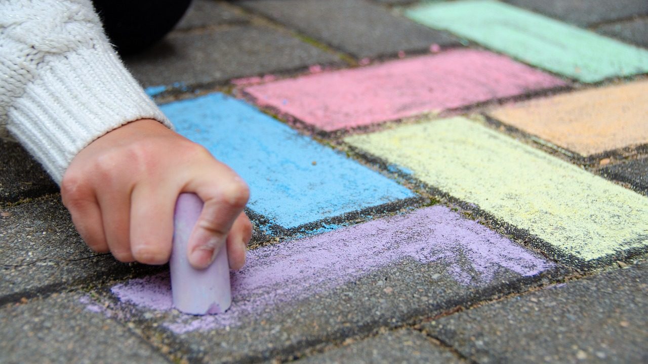 Kind speelt met stoepkrijt op straat